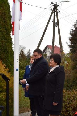 Przewodniczący Rady Gminy Wyryki Piotr Horszczaruk wraz z radnymi Jolantą Stepaniuk i Alicją Kuszpa dokonuje uroczystego wciągnięcia flagi na nowy maszt